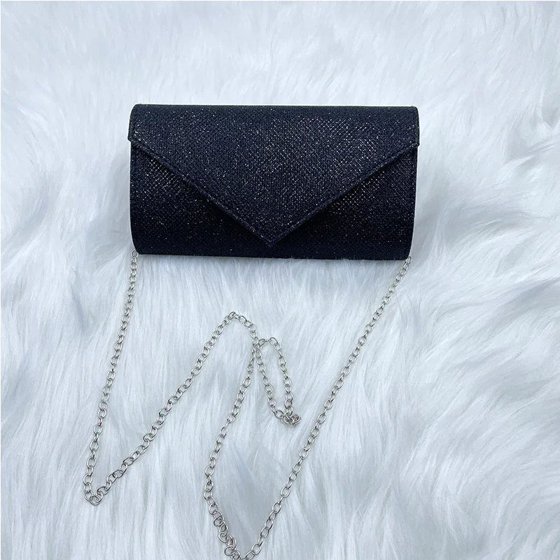 Black glitter clutch purse with silver chain strap on white faux fur background