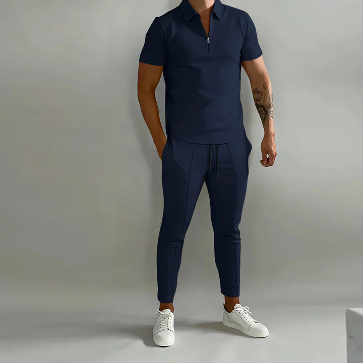 Man wearing a navy blue short-sleeve polo shirt and matching jogger pants with white sneakers