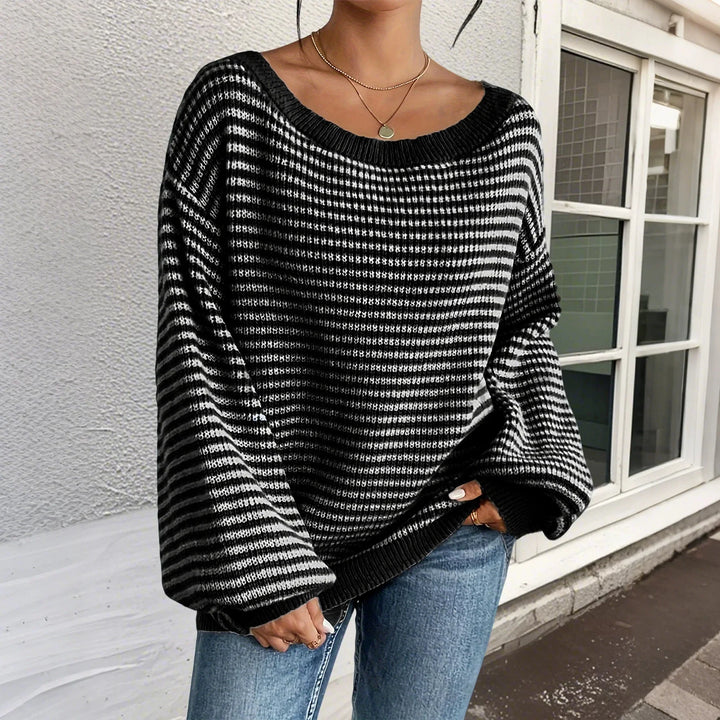 Woman wearing oversized black and white striped knit sweater with blue jeans and layered necklaces