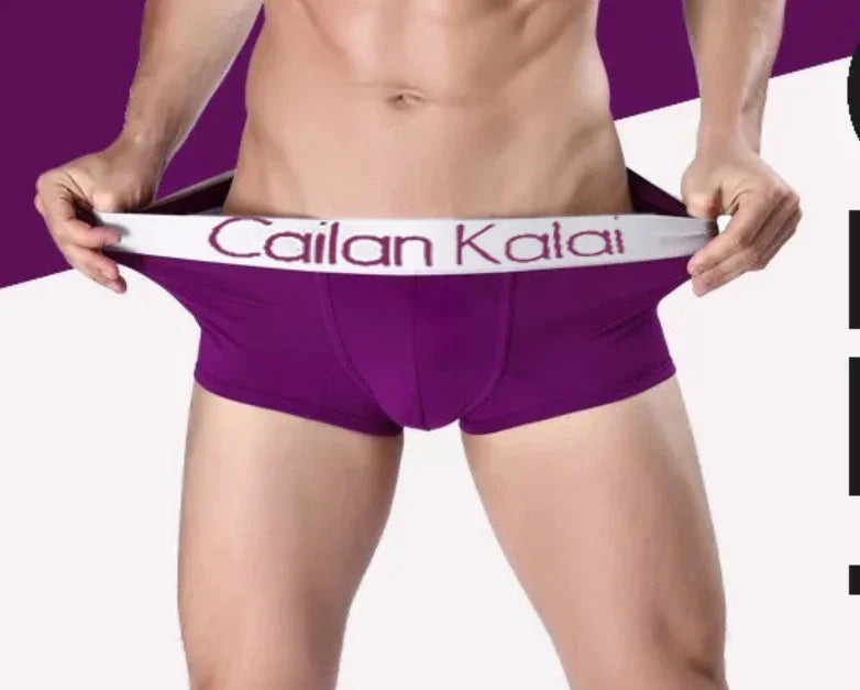 Male model wearing purple Cailan Kalai branded boxer briefs, stretching waistband in studio