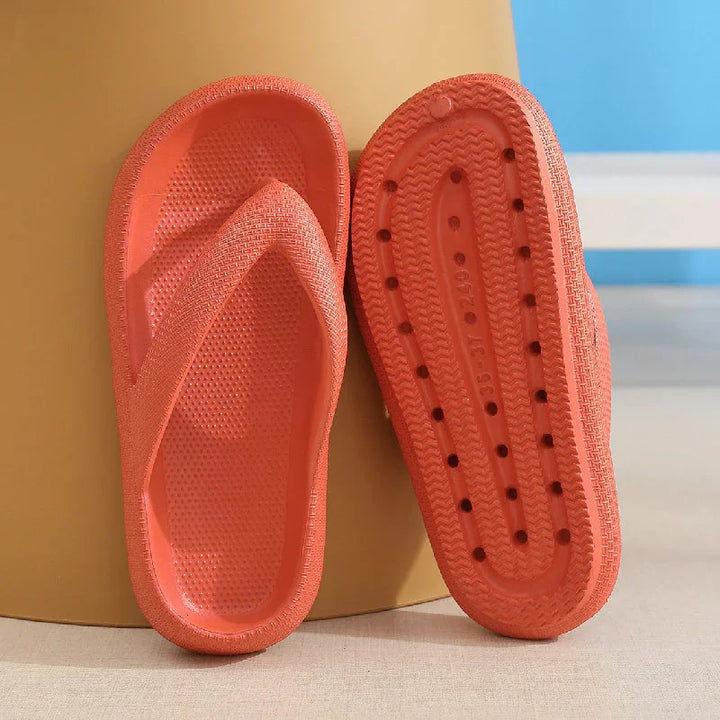 Pair of bright orange textured rubber flip flops with ventilation holes on sole