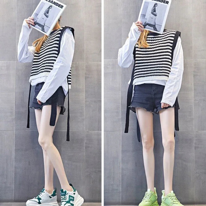Woman in black and white striped knit vest, white long-sleeve shirt, black shorts, and sneakers holding magazine over face