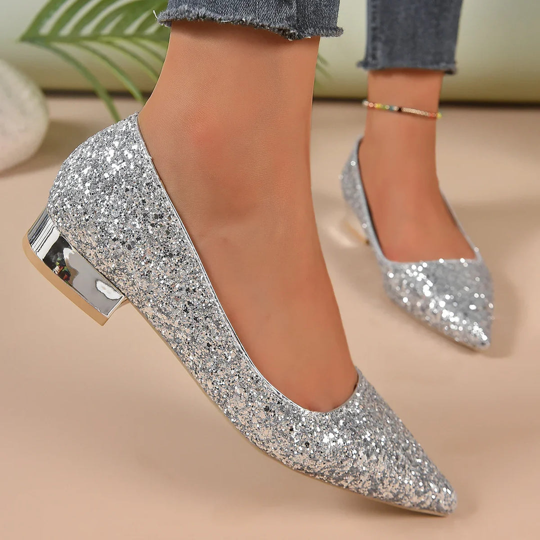 Pair of silver glitter pointed-toe low block heel shoes worn with cropped jeans and colorful anklet
