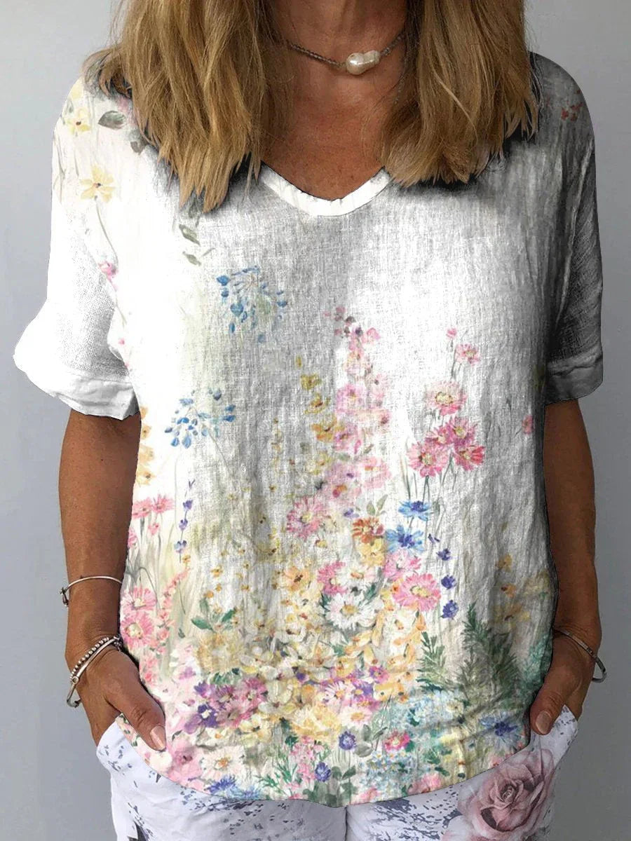 Woman wearing a white V-neck shirt with colorful floral print and casual floral pants