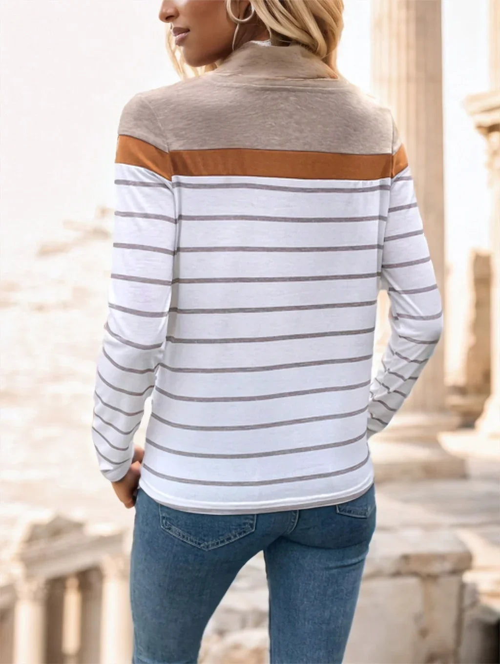 Woman wearing striped long-sleeve top with beige, brown, and white colors, paired with blue jeans