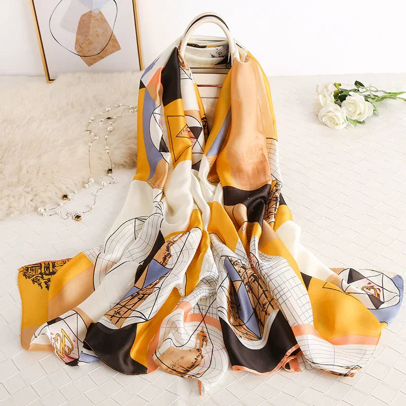 Colorful geometric patterned silk scarf draped over a white chair on quilted surface with white roses and decorative beads