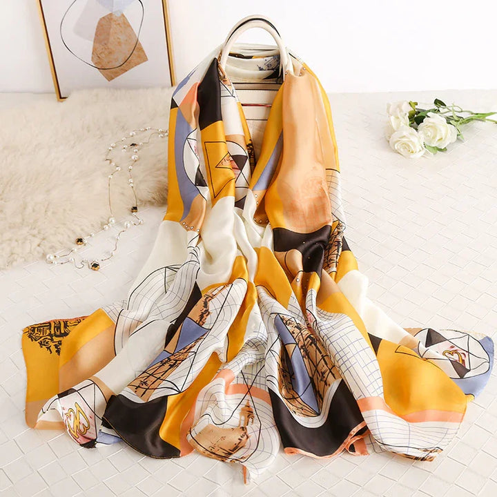 Colorful geometric patterned silk scarf draped over a white chair on quilted surface with white roses and decorative beads