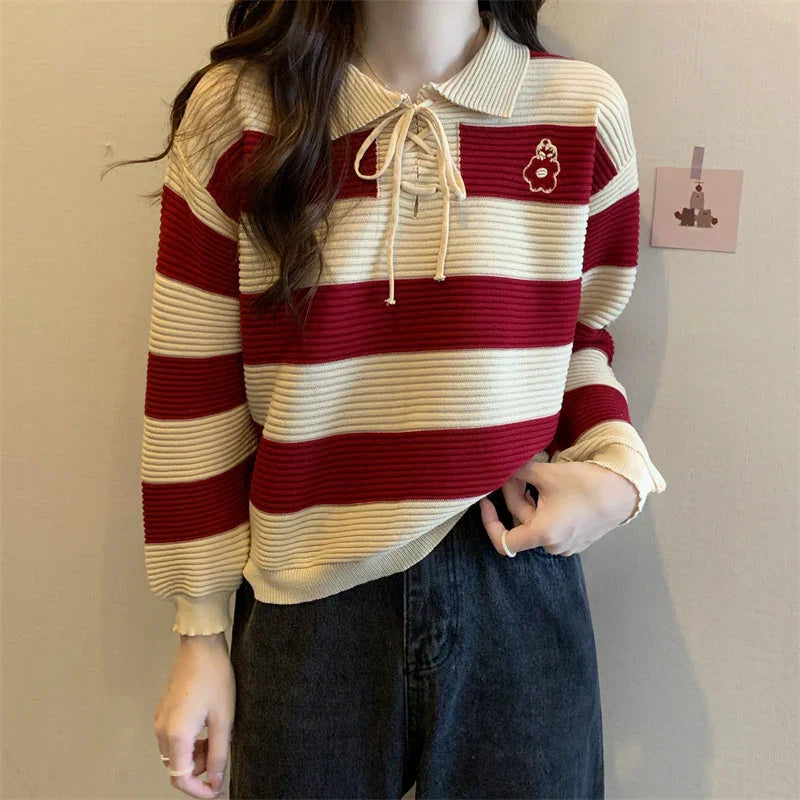 Woman wearing red and beige striped knit sweater with collar and lace-up neck detail