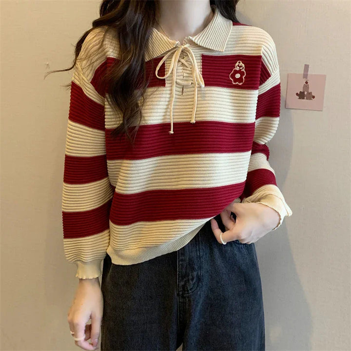 Woman wearing red and beige striped knit sweater with collar and lace-up neck detail