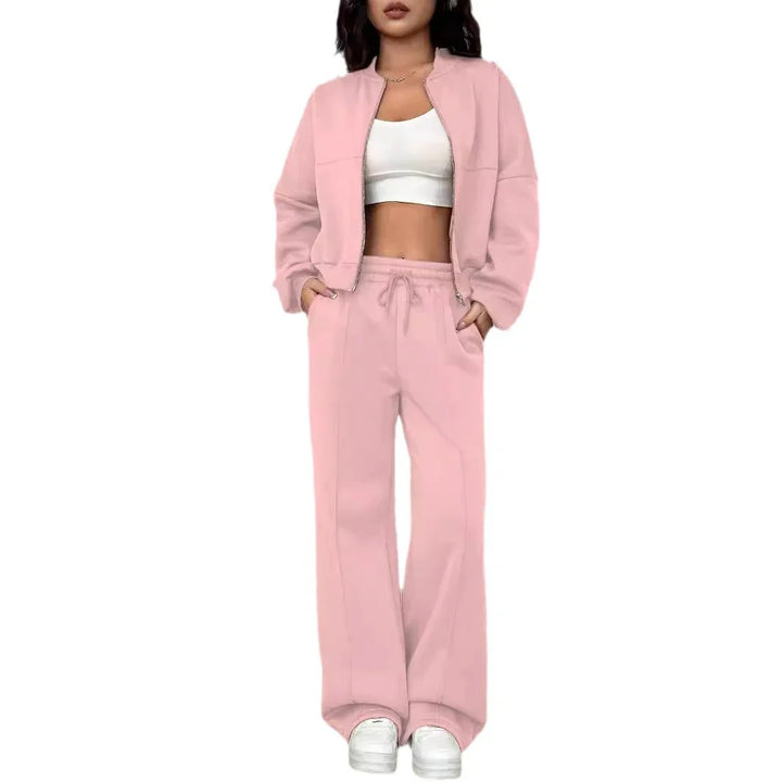 Woman wearing light pink zip-up jacket and wide-leg pants with white crop top and sneakers