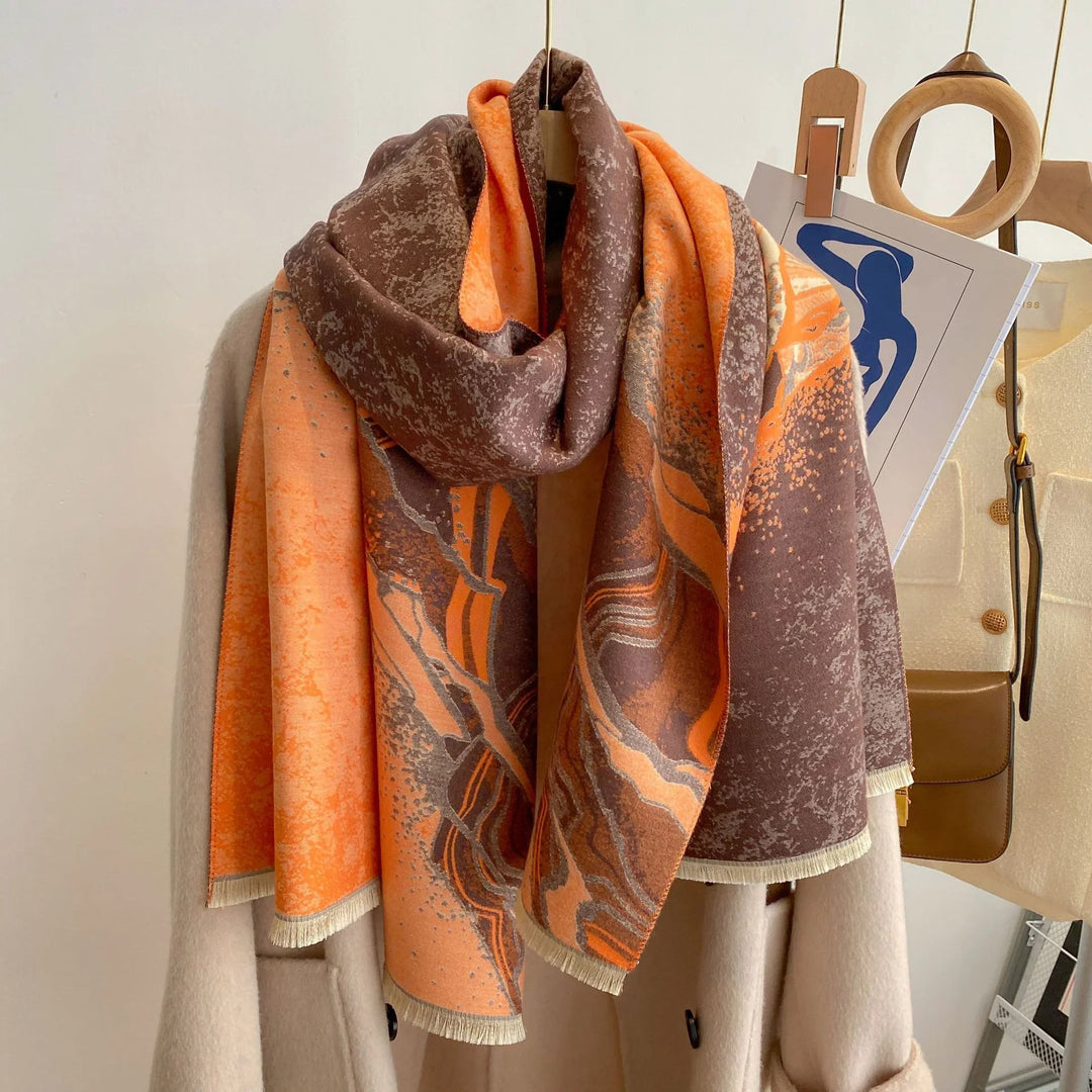 Orange and brown abstract patterned scarf draped over beige coat on wooden hanger