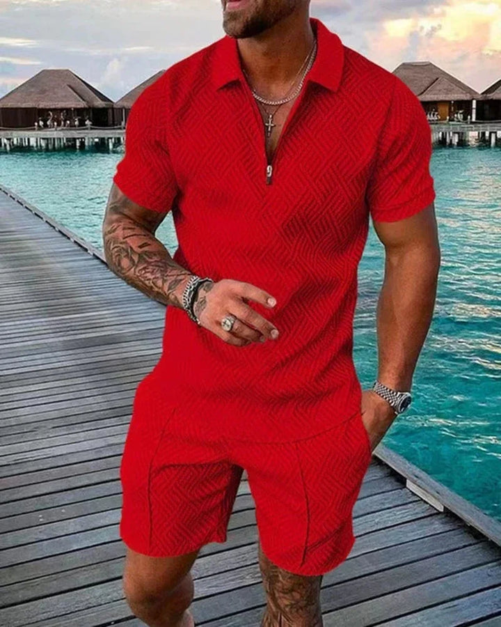 Man wearing red textured short-sleeve polo shirt and shorts on wooden pier by ocean bungalows
