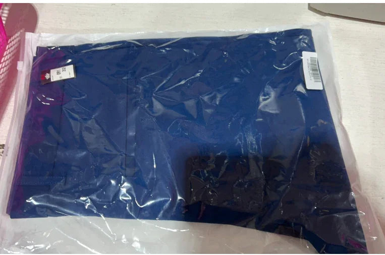Blue clothing item packed in transparent plastic bag on white surface with size label