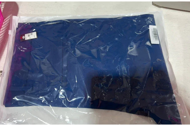 Blue clothing item packed in transparent plastic bag on white surface with size label
