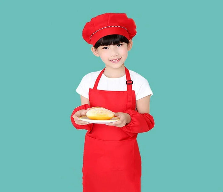 Smiling girl in red chef hat and apron holding a plate with a powdered sugar bun on blue background