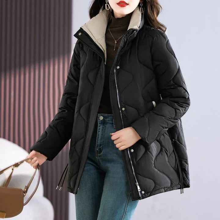 Woman wearing black quilted winter coat with beige collar, paired with blue jeans and brown handbag