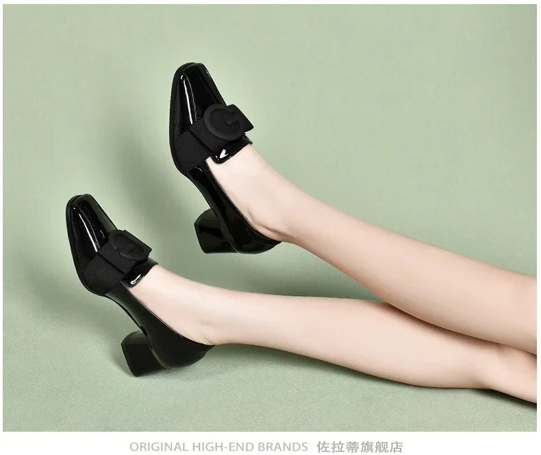 Woman wearing black patent leather block heel shoes with black buckle straps on green background
