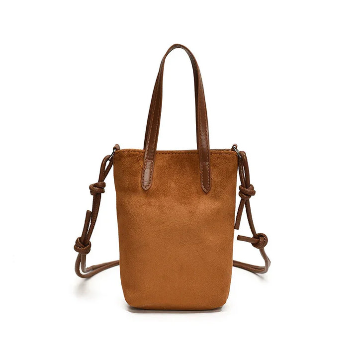 Small brown suede handbag with leather handles and adjustable knotted shoulder strap on white background