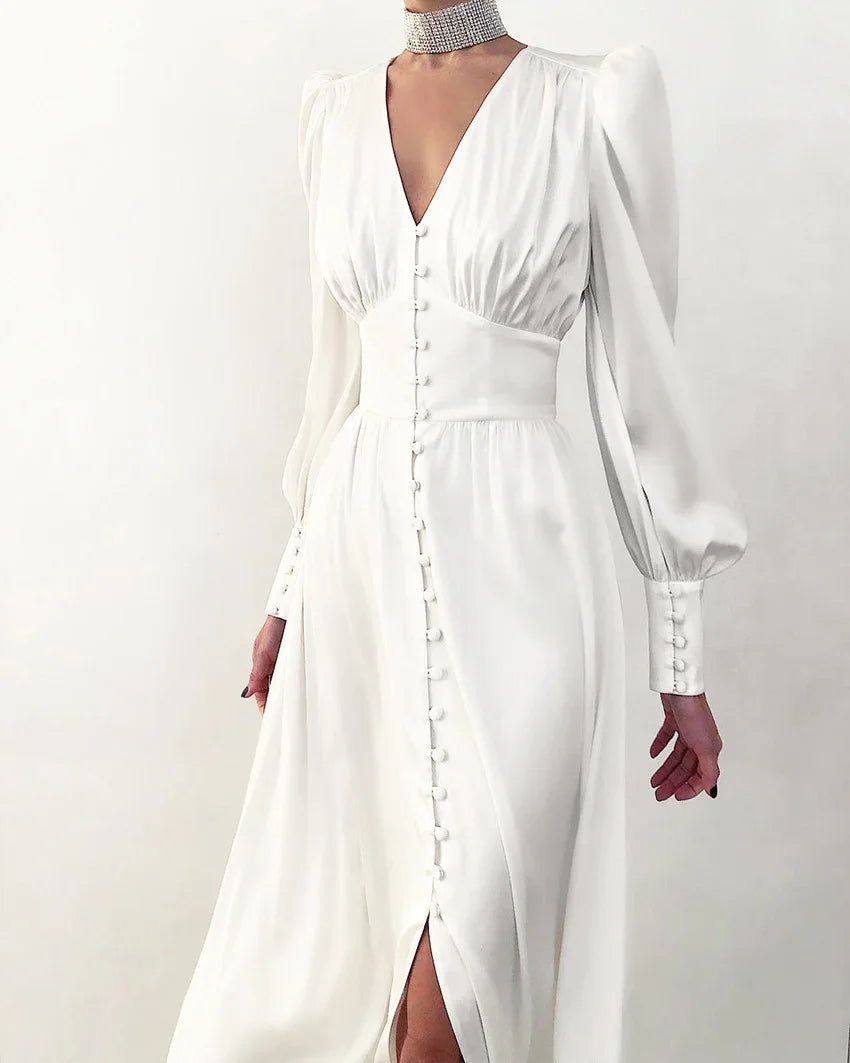 Woman wearing elegant white long-sleeve dress with button details and deep V-neck