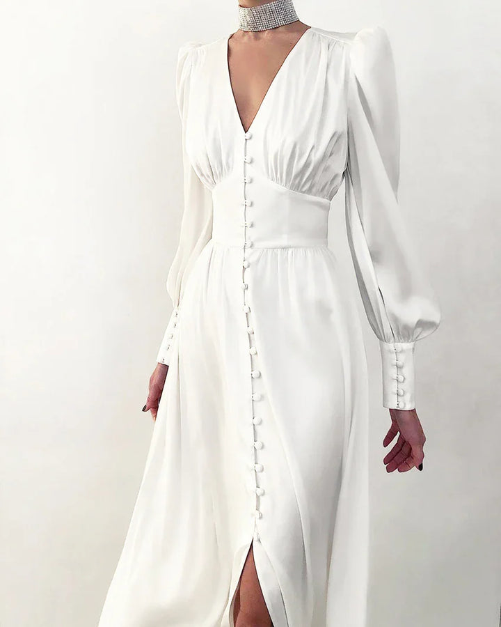 Woman wearing elegant white long-sleeve dress with button details and deep V-neck