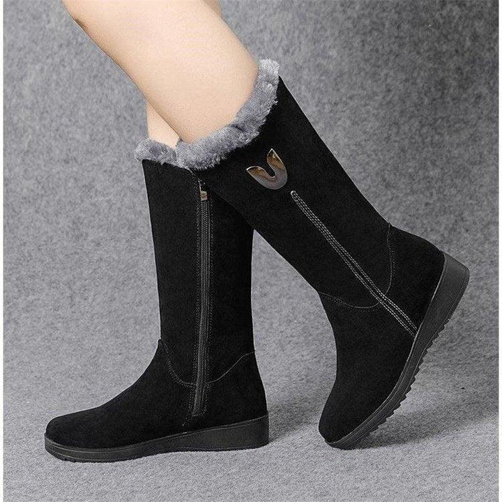 Black suede knee-high winter boots with gray fur lining and side zipper, on gray textured background