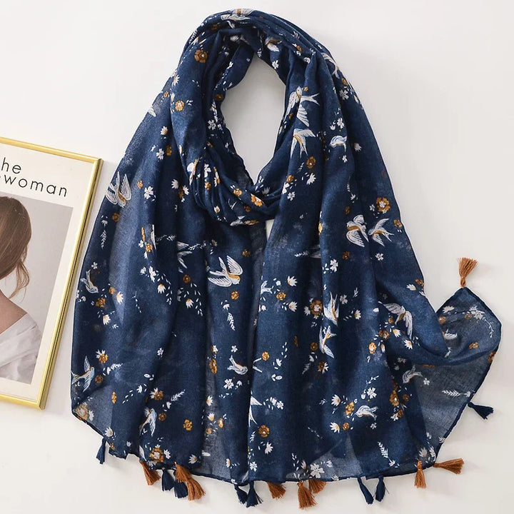 Navy blue floral scarf with bird print and tassels, displayed alongside a framed photo on white background