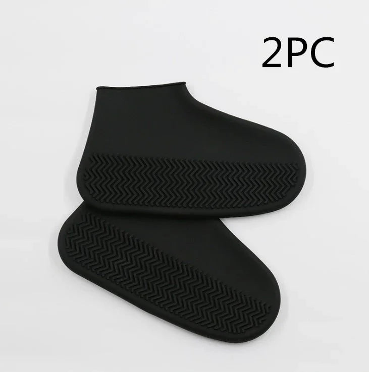 Pair of black silicone waterproof shoe covers with textured non-slip soles on white background