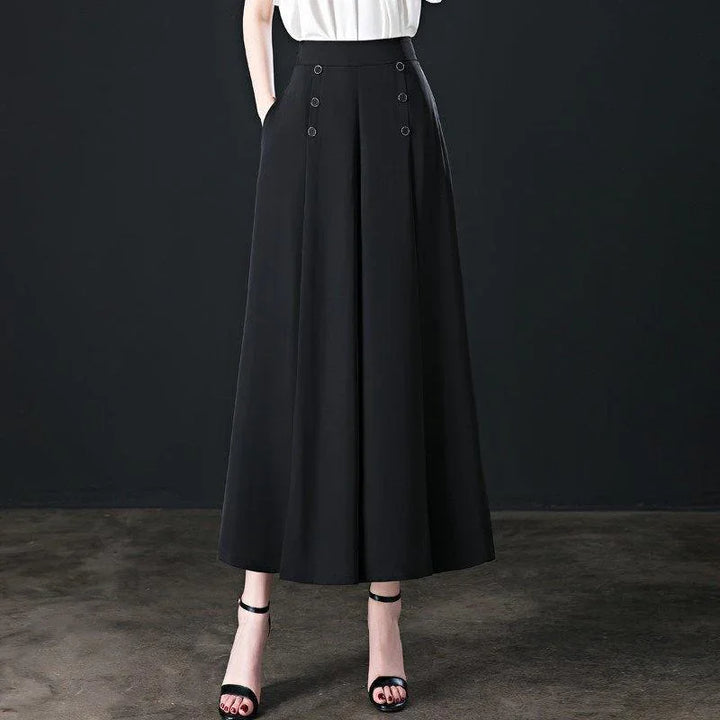 Woman wearing high-waisted black wide-leg culottes with front button details and black ankle-strap heels