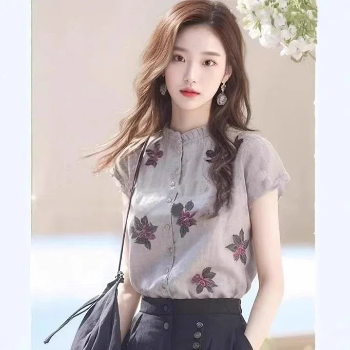 Young woman wearing a floral embroidered blouse and high-waisted black skirt, posing indoors