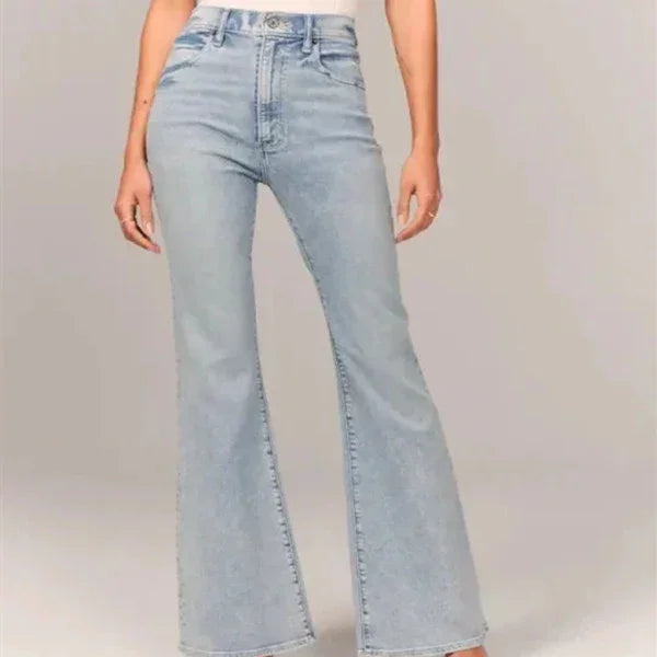 woman wearing light blue high-waisted flared jeans on neutral background