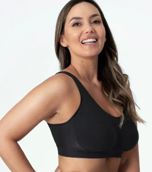 Smiling woman wearing a black seamless sports bra with long wavy brown hair on white background