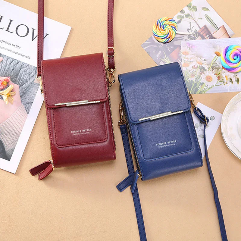 Two small crossbody bags in burgundy and navy blue leather with front flap and zipper, styled with decorative postcards and lollipops