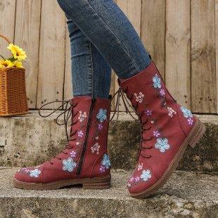 Red leather ankle boots with blue and white floral embroidery worn with blue jeans on stone steps