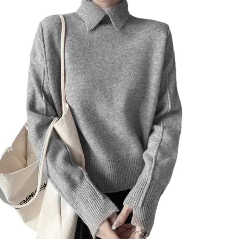 Person wearing a cozy gray knit sweater with ribbed cuffs and collar, holding a beige tote bag