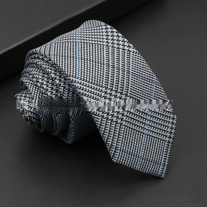 Rolled gray and black checkered necktie with subtle blue stripes on black surface