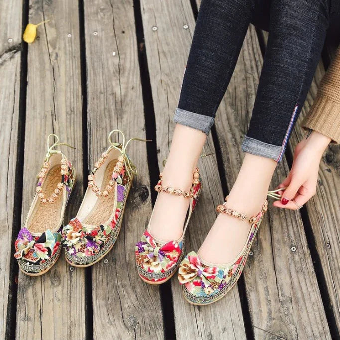 Woman wearing colorful floral embroidered flat shoes with ankle straps on wooden floor