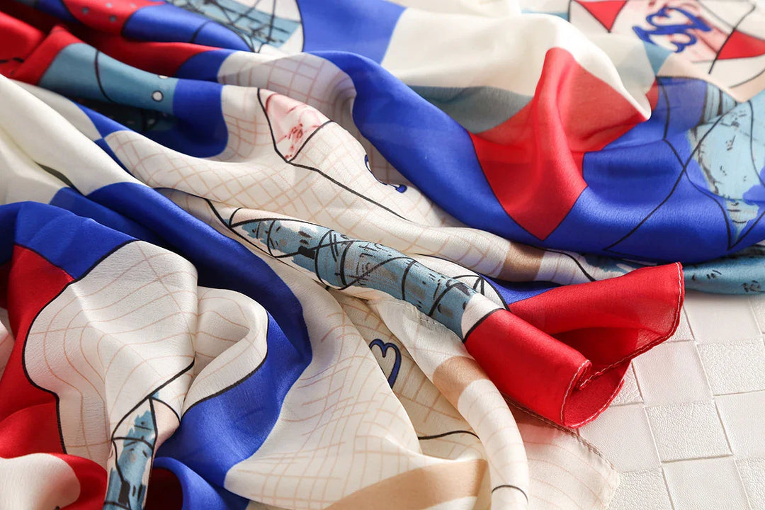 Close-up of colorful patterned silk scarf with red, blue, beige, and black details on white surface