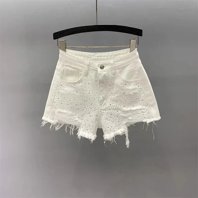 White distressed denim shorts with rhinestone embellishments hanging on black hanger