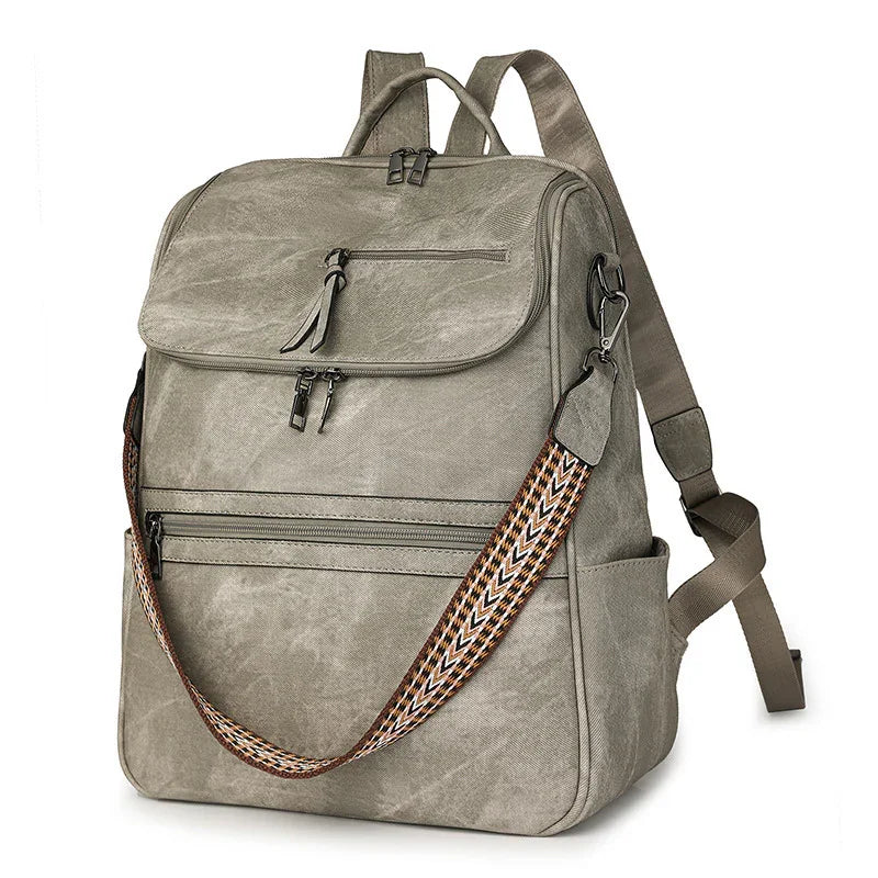 Grey canvas backpack with multiple zippered compartments and a removable patterned shoulder strap