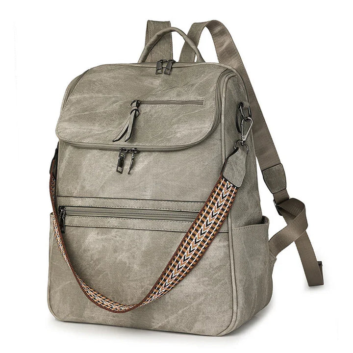 Grey canvas backpack with multiple zippered compartments and a removable patterned shoulder strap