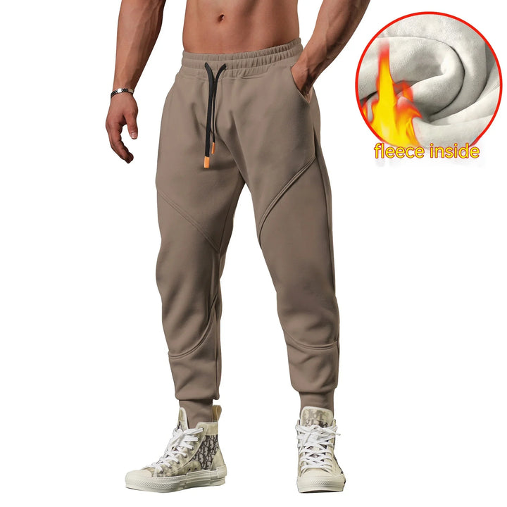 Man wearing beige fleece-lined jogger pants with black drawstrings and high-top patterned sneakers