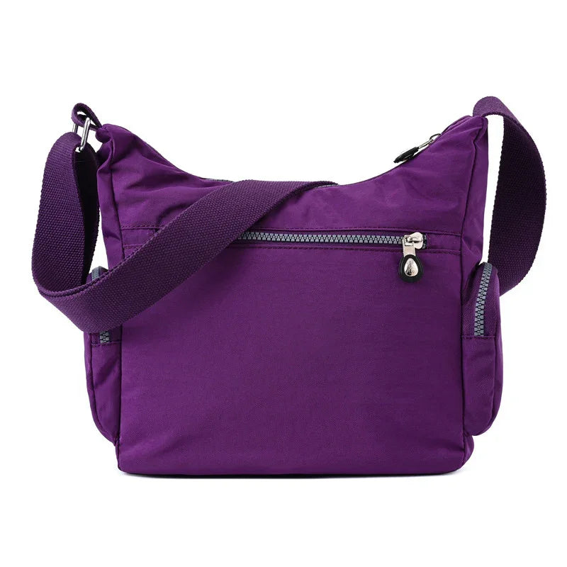 Purple crossbody bag with adjustable strap, front zipper pocket, and side compartments