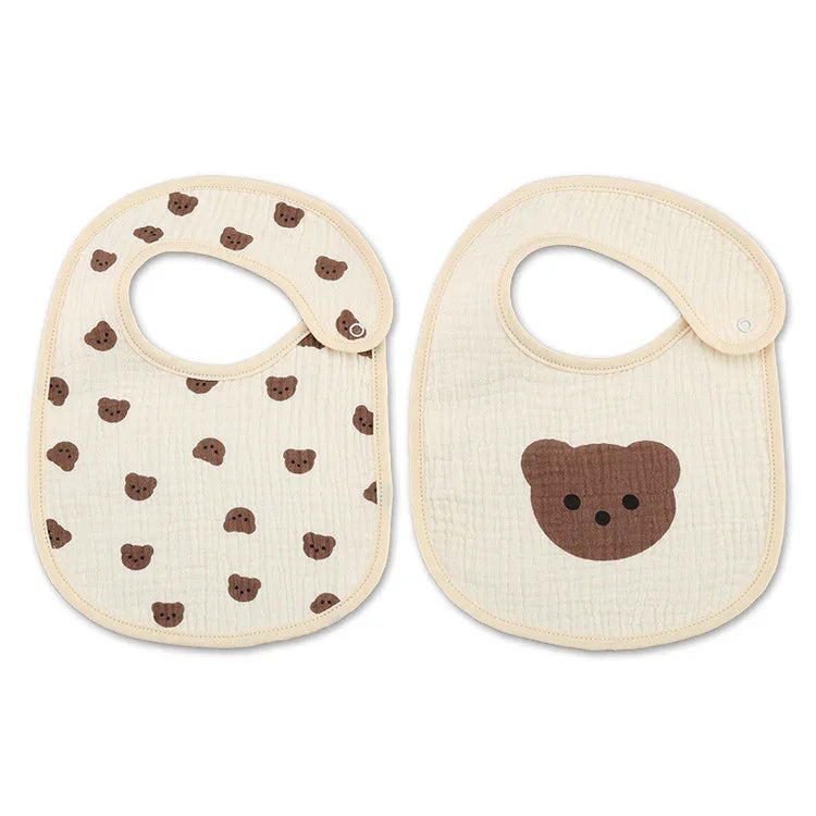 Two beige baby bibs with brown bear face prints, one with scattered bears and one with a single large bear face