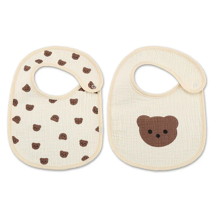 Two beige baby bibs with brown bear face prints, one with scattered bears and one with a single large bear face