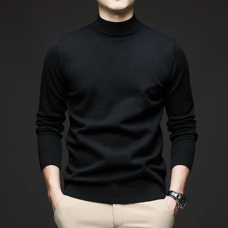 Man wearing black turtleneck sweater with beige pants and wristwatch against dark background