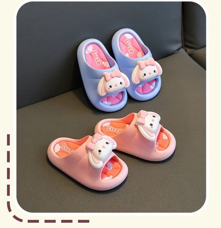 Children's open-toe slippers in pink and blue with cute bunny faces and bows on black surface