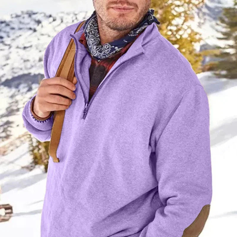 Man wearing lavender quarter-zip fleece sweater with brown elbow patches outdoors in snowy winter landscape