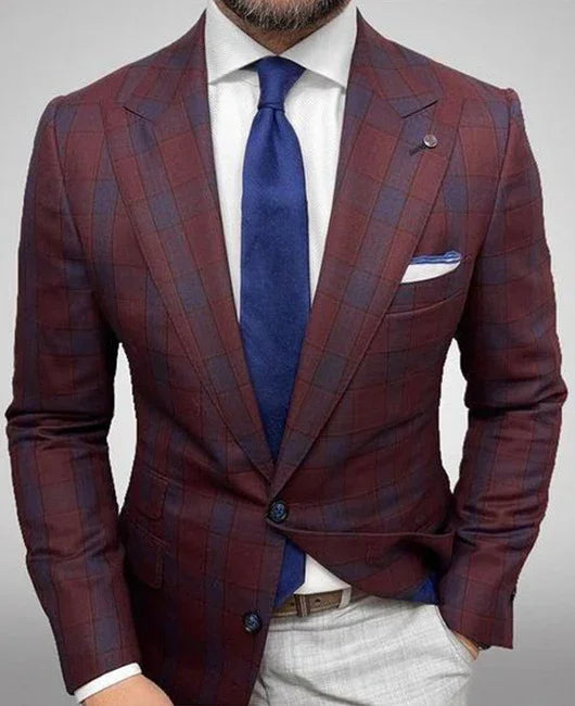 Man wearing a tailored burgundy checkered blazer with blue tie, white shirt, and light grey pants