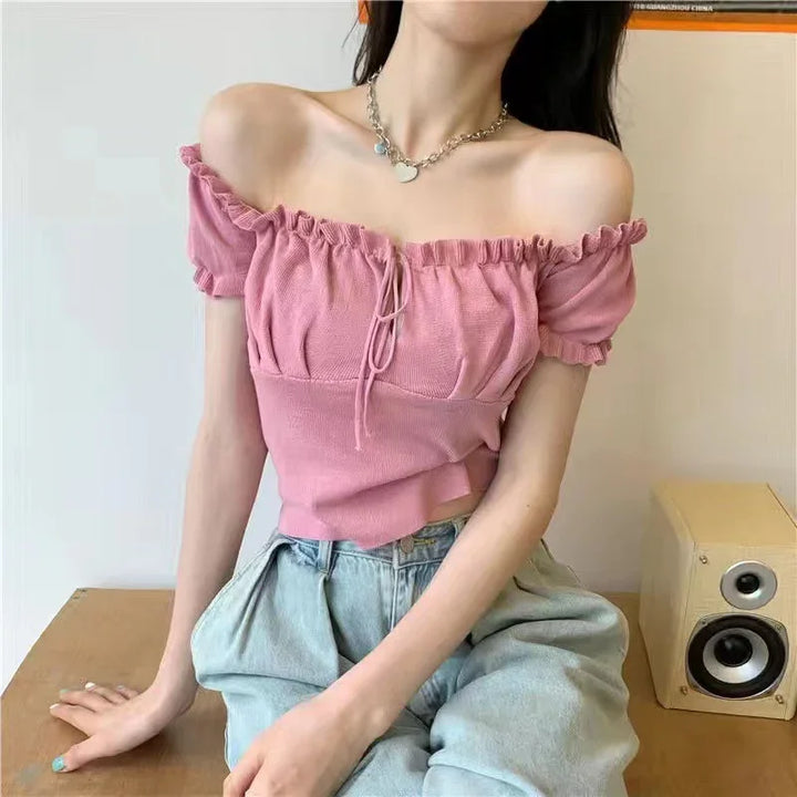 Woman wearing pink off-shoulder ruffle crop top paired with light blue high-waisted jeans, silver necklace