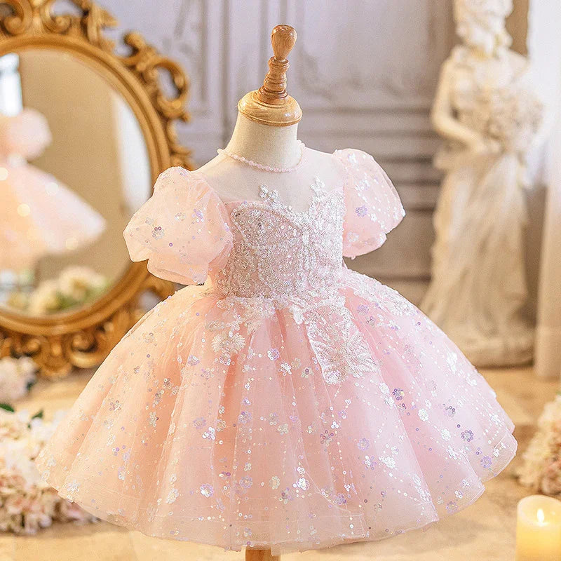 Pink toddler dress with puff sleeves and sequin floral embroidery on mannequin in elegant room